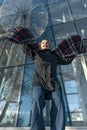 Laughing young woman jumps against glass facade of building with transparent umbrella. Vertical frame. Bottom view