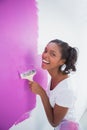 Laughing young woman painting her wall in pink