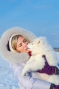 Laughing young woman and samoyed puppy kiss on winter frosty day Royalty Free Stock Photo