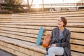 Young laughing woman with a skateboard is sitting on a 2-stage bench. Royalty Free Stock Photo