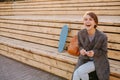 Young laughing woman with a skateboard is sitting on a 2-stage bench. Royalty Free Stock Photo