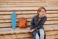 Young laughing woman with a skateboard is sitting on a 2-stage bench. Royalty Free Stock Photo