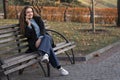 Laughing young woman sitting on bench in park talking on phone and smile. Young woman uses smartphone Royalty Free Stock Photo