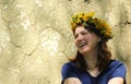 Laughing young woman wearing a dandelion wreath against old cracked wall
