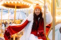 Laughing young woman at the winter fair riding a horse, carousel, Christmas carelessness and fun.