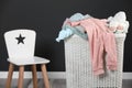 Laundry basket with baby clothes and white wooden chair indoors Royalty Free Stock Photo