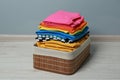 Laundry basket with clean stacked clothes on floor near grey wall