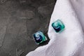 Laundry capsules and a snow-white towel on a black marble background