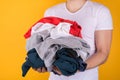 Laundry concept. Cropped half turned photo of man holding lots of clothes on yellow background