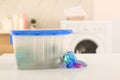 Laundry container and washing detergent capsules on table indoors Royalty Free Stock Photo