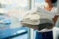 Laundry day done and dusted. a young woman carrying a pile of towels on laundry day at home.