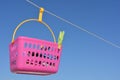 Clothes pegs in a pink basket hanging from clothesline Royalty Free Stock Photo