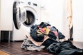 Laundry day. Washing machine in the background, pile of dirty clothes on the floor. Family house chores and domestic work concept Royalty Free Stock Photo