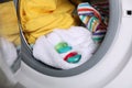 Laundry detergent capsules and clothes in washing machine drum, closeup view Royalty Free Stock Photo