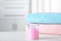 Laundry detergent in measuring cup near stacked folded towels on table
