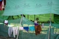 Laundry hang-drying by a green tarp shelter in Myanmar