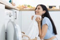 Laundry and housework concept. Happy woman housewife doing laundry on vacation. Female is putting clothes into washing machine Royalty Free Stock Photo