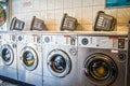 Laundry or landrette  with coin  operated front loading washing machines and landry baskets on top Royalty Free Stock Photo