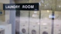 A laundry room sign on a window Infront of some washing machines