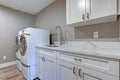 Laundry room with taupe walls and marble top cabinets.