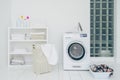 Laundry room with washing machine, dirty clothes in basket, iron and little shelf with neatly folded linen. Domestic room interior Royalty Free Stock Photo