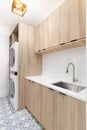 A laundry room with wood cabinets, pattern tile floor, and white appliances.