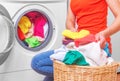 Young woman loads the laundry in the washing machine from the laundry basket before washing. Royalty Free Stock Photo