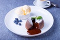 Lava cake with dripping filling. Chocolate fondant cake with vanilla ice cream, blueberries, mint and coffee. Royalty Free Stock Photo
