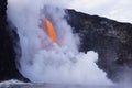 Lava flowing out of cliff suround with white cloud steam Royalty Free Stock Photo