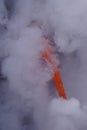 Lava flowing out of cliff suround with white cloud steam