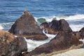 Lava rock outcrop formations in the Pacific surf with crashing wave and rainbows