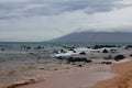 Lava rocks strewn across the waters of the Pacific Ocean and the sandy beach of Ma`alaea Bay, Maui, Hawaii