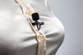 The lavalier microphone is secured with a clip on a women shirt close-up. Audio recording of the sound of the voice on a condenser