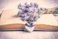 Lavender bouquet laid over an old book and a silver heart on a white wooden background. Vintage style. Royalty Free Stock Photo