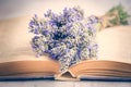 Lavender bouquet laid over an old book on a white wooden background. Vintage style.