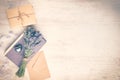 Lavender bouquet laid over an old book, a wrapped gift box, a kraft paper envelope and a silver heart on a white wooden backgroun Royalty Free Stock Photo