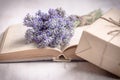 Lavender bouquet laid over an old book and a wrapped gift box on a white wooden background. Vintage style. Royalty Free Stock Photo