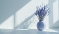 Lavender bouquet in white vase against the wall in room with blue light and texturing shadow. space for text