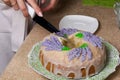 Lavender Cupcake. Sugar coated. Decorated with lavender glaze flowers. A woman cuts a small piece from him