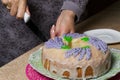 Lavender Cupcake. Sugar coated. Decorated with lavender glaze flowers. A woman cuts a small piece from him