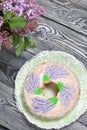 Lavender Cupcake. Sugar coated. Decorated with lavender glaze flowers. Near a vase with a bouquet of lilacs