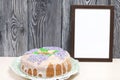 Lavender Cupcake. Sugar coated. Decorated with lavender glaze flowers. Nearby is an empty photo frame