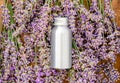 Lavender essential oil metal silver bottle on fresh lavender flowers. Flat lay apothecary herbs for aromatherapy treatment.