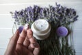 Lavender flowers, candles, cream and female hand on a white wooden background. Royalty Free Stock Photo