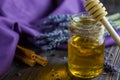 Lavender and herbal honey in glass jar with honey spoon on dark wooden background