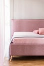 Lavender purple blanket on a pink bed with upholstered headboard