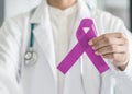 Lavender purple cancer all kinds awareness ribbon on doctor`s hand support for national cancer survivor month campaign Royalty Free Stock Photo