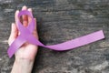 Lavender purple cancer all kinds awareness ribbon on people`s hand support with aged wood background Royalty Free Stock Photo