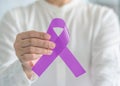 Lavender purple cancer awareness ribbon on person`s hand, symbolic bow color  to support patient with all kinds tumor Royalty Free Stock Photo