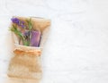 Lavender Scented Soap and Flower Blossoms with Fresh Green Leaves folded in a Tan Washcloth on Bathroom Gray and White Marble Surf